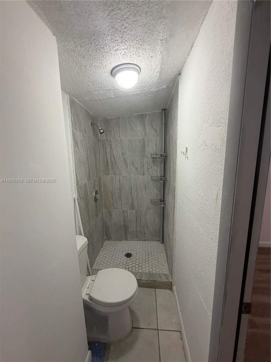 2980 Northwest 79th Street, Unit A Miami, FL 33147 - Photo 6 of 7 a bathroom with a granite countertop toilet and a shower