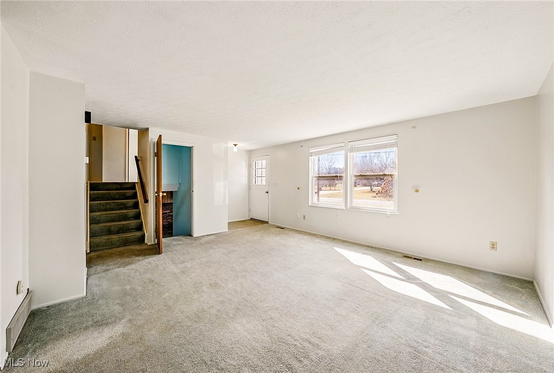 803 Renninger Road Akron, OH 44319 - Photo 3 of 44 Unfurnished living room with stairway, light carpet, and visible vents