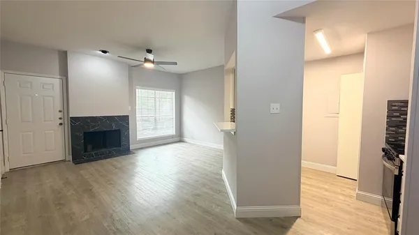 a view of a livingroom with a fireplace a ceiling fan and wooden floor
