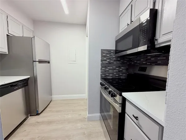 a kitchen with stainless steel appliances white cabinets and a stove top oven