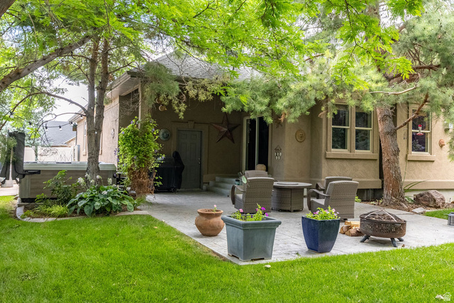288 525 South Providence, UT 84332 - Photo 61 of 71 Expansive concrete patio with integrated hot tub, mature trees, stucco exterior, and sliding glass door access
