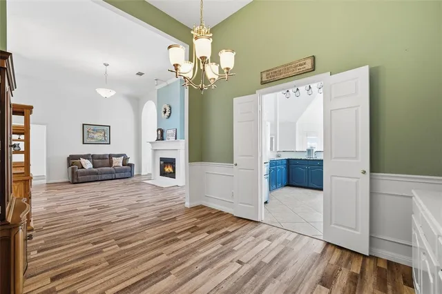 a view of a livingroom with a fireplace a chandelier and wooden floor