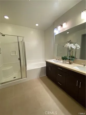 a spacious bathroom with a double vanity sink a large mirror and a bathtub