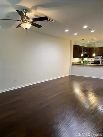 a view of a livingroom with a flat screen tv wooden floor and a ceiling fan