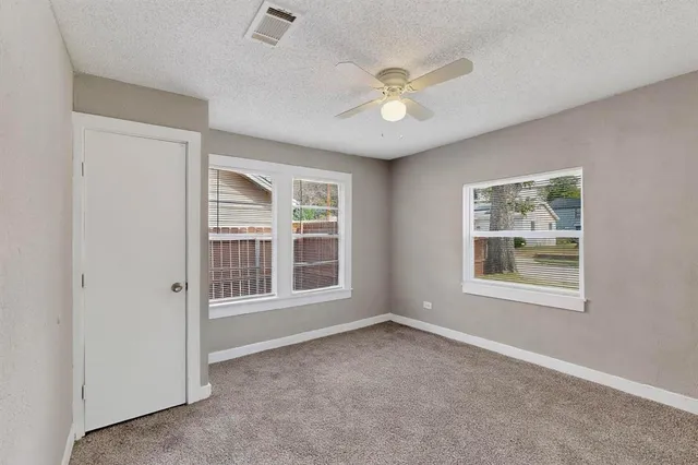 an empty room with windows and fan