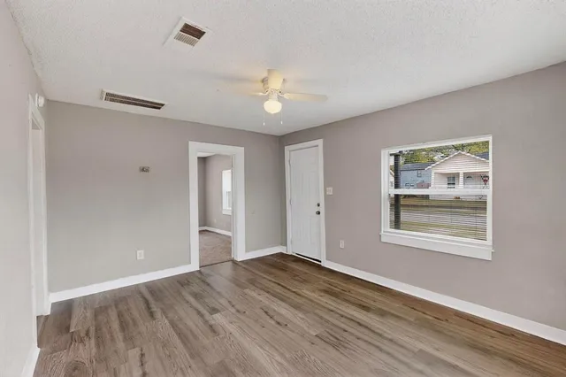 a view of an empty room with wooden floor and a window