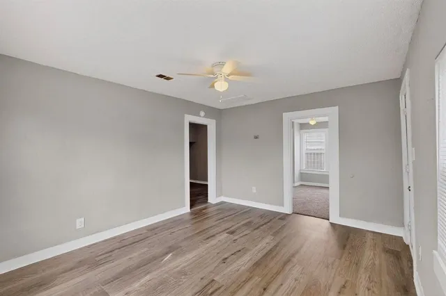 a view of empty room with wooden floor and ceiling fan