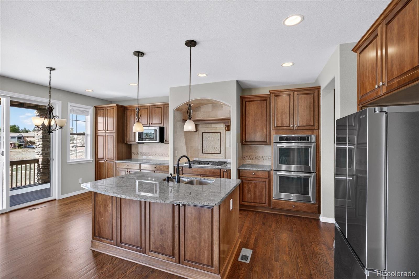 10872 Valleybrook Circle Highlands Ranch, CO 80130 - Photo 13 of 50 a kitchen with stainless steel appliances granite countertop a sink refrigerator and cabinets