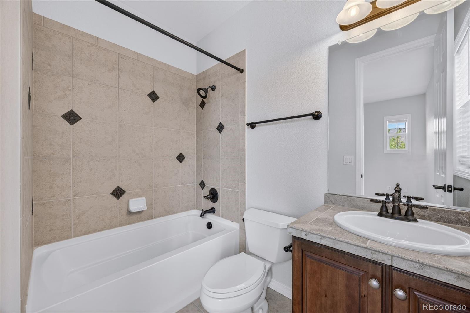10872 Valleybrook Circle Highlands Ranch, CO 80130 - Photo 32 of 50 a bathroom with a granite countertop sink a toilet a mirror a bathtub and shower