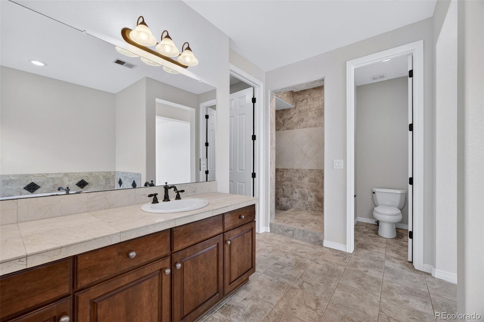 10872 Valleybrook Circle Highlands Ranch, CO 80130 - Photo 39 of 50 a spacious bathroom with a double vanity sink toilet mirror and double