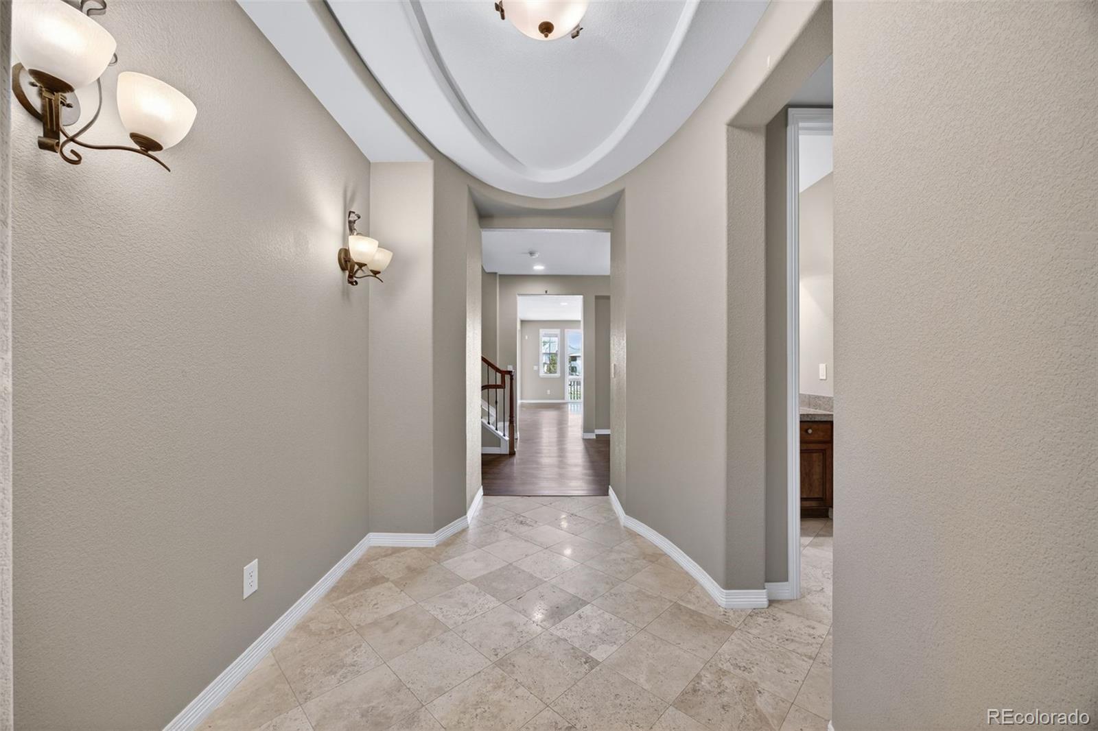 10872 Valleybrook Circle Highlands Ranch, CO 80130 - Photo 4 of 50 a view of a hallway with wooden floor and a chandelier