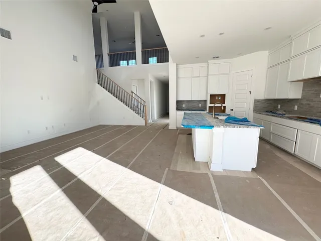 a kitchen with stainless steel appliances kitchen island granite countertop a refrigerator a stove and white cabinets with wooden floor