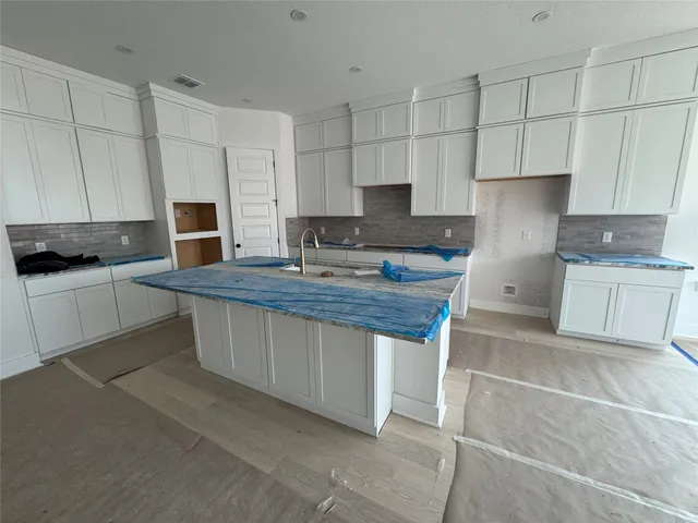 a kitchen with kitchen island granite countertop a sink cabinets and stainless steel appliances
