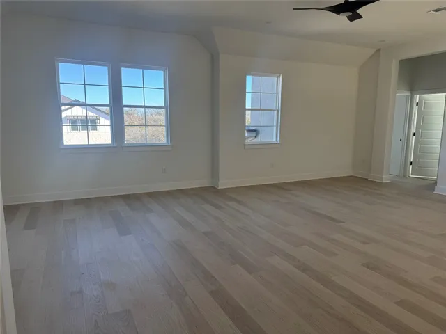 an empty room with wooden floor cabinet and windows