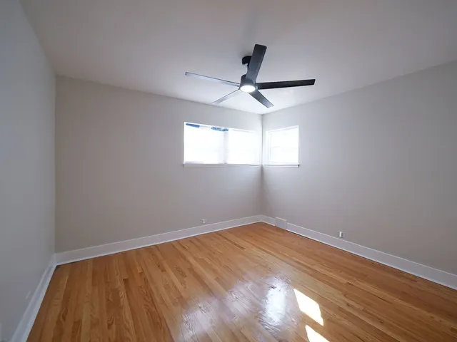 an empty room with a window and ceiling fan