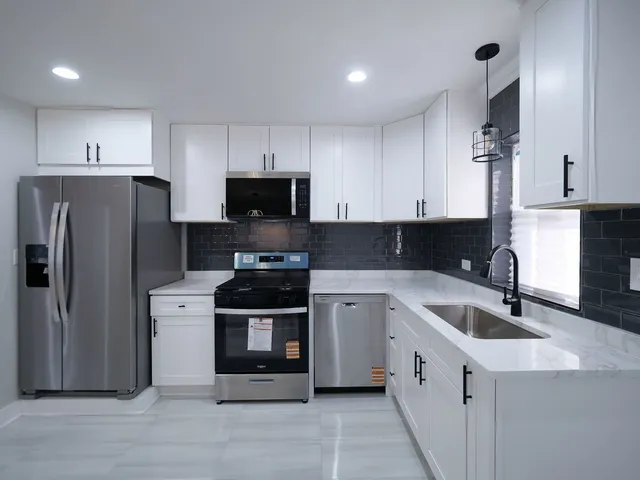 a kitchen with stainless steel appliances granite countertop a refrigerator sink and white cabinets