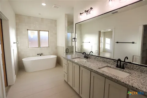 a bathroom with a granite countertop bathtub a double vanity sink and mirror