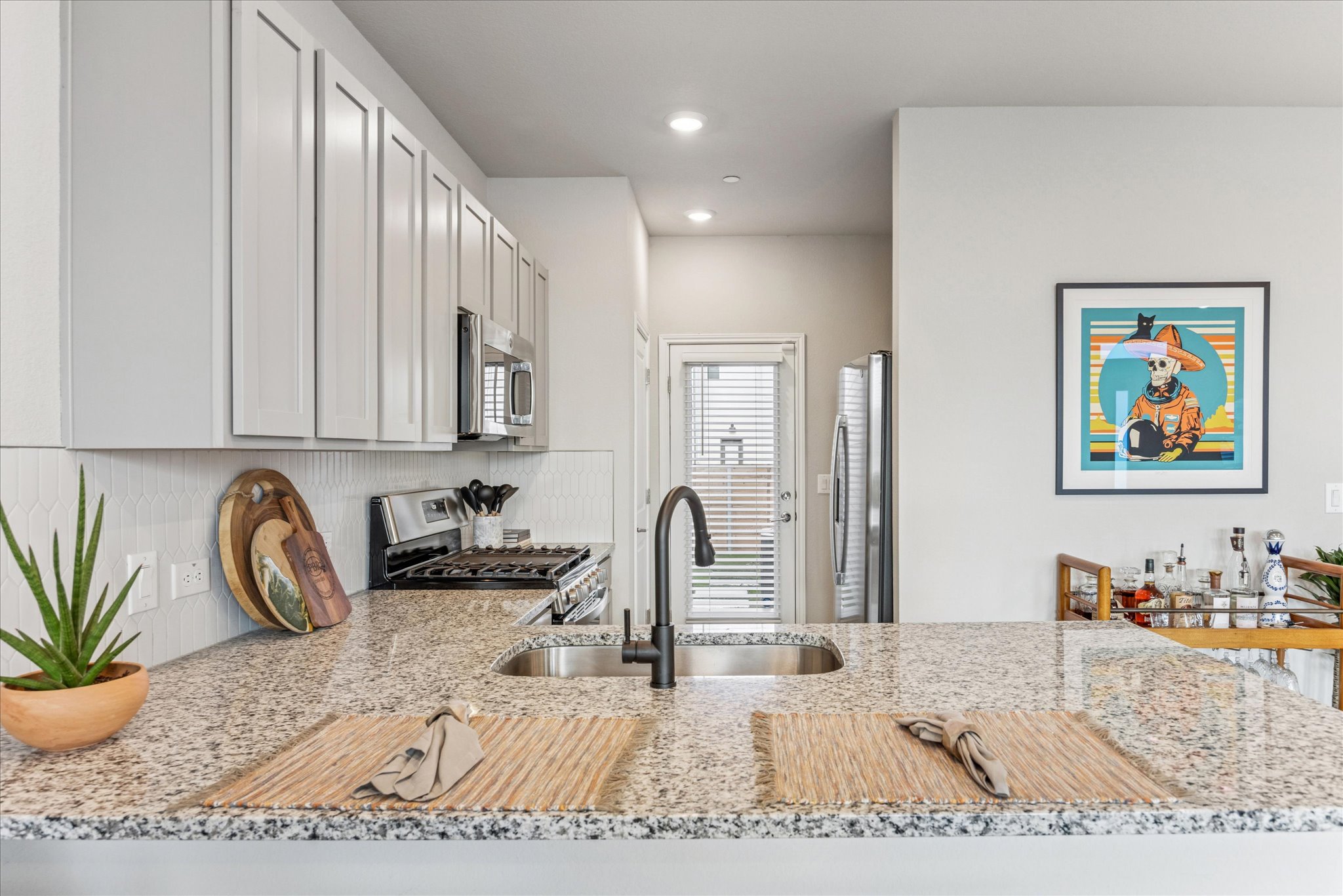 9015 Cattle Baron Path, Unit 1002 Austin, TX 78747 - Photo 7 of 20 a kitchen with stainless steel appliances granite countertop a sink a stove a dining table and chairs with wooden floor