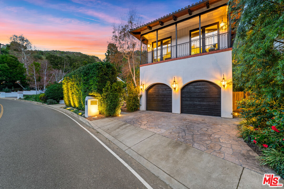 3606 Mandeville Canyon Road Los Angeles, CA 90049 - Photo 22 of 32 a front view of a house with yard and parking