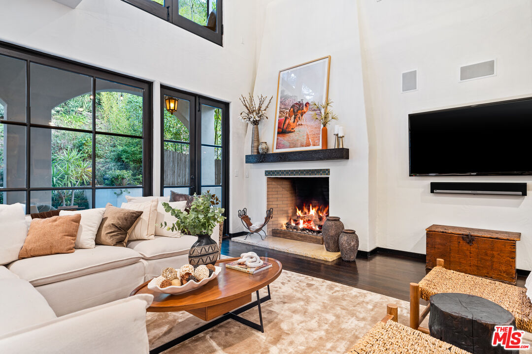 3606 Mandeville Canyon Road Los Angeles, CA 90049 - Photo 8 of 32 a living room with furniture a flat screen tv and a fireplace