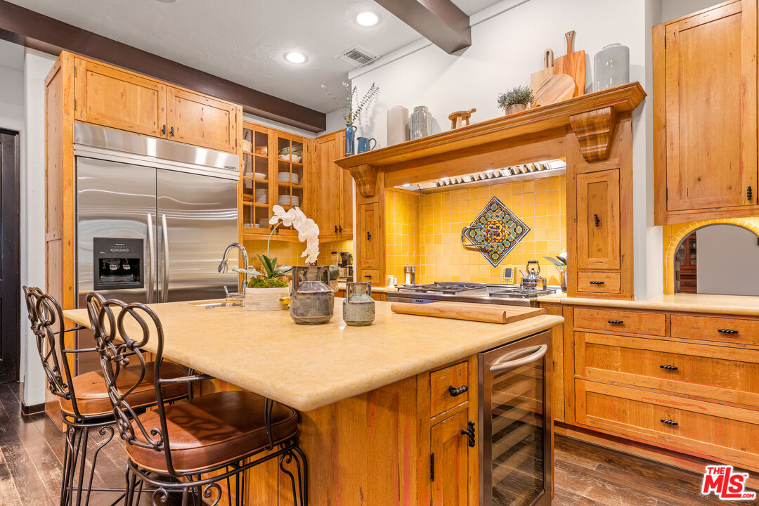 3606 Mandeville Canyon Road Los Angeles, CA 90049 - Photo 9 of 32 a kitchen with a sink a stove and chairs