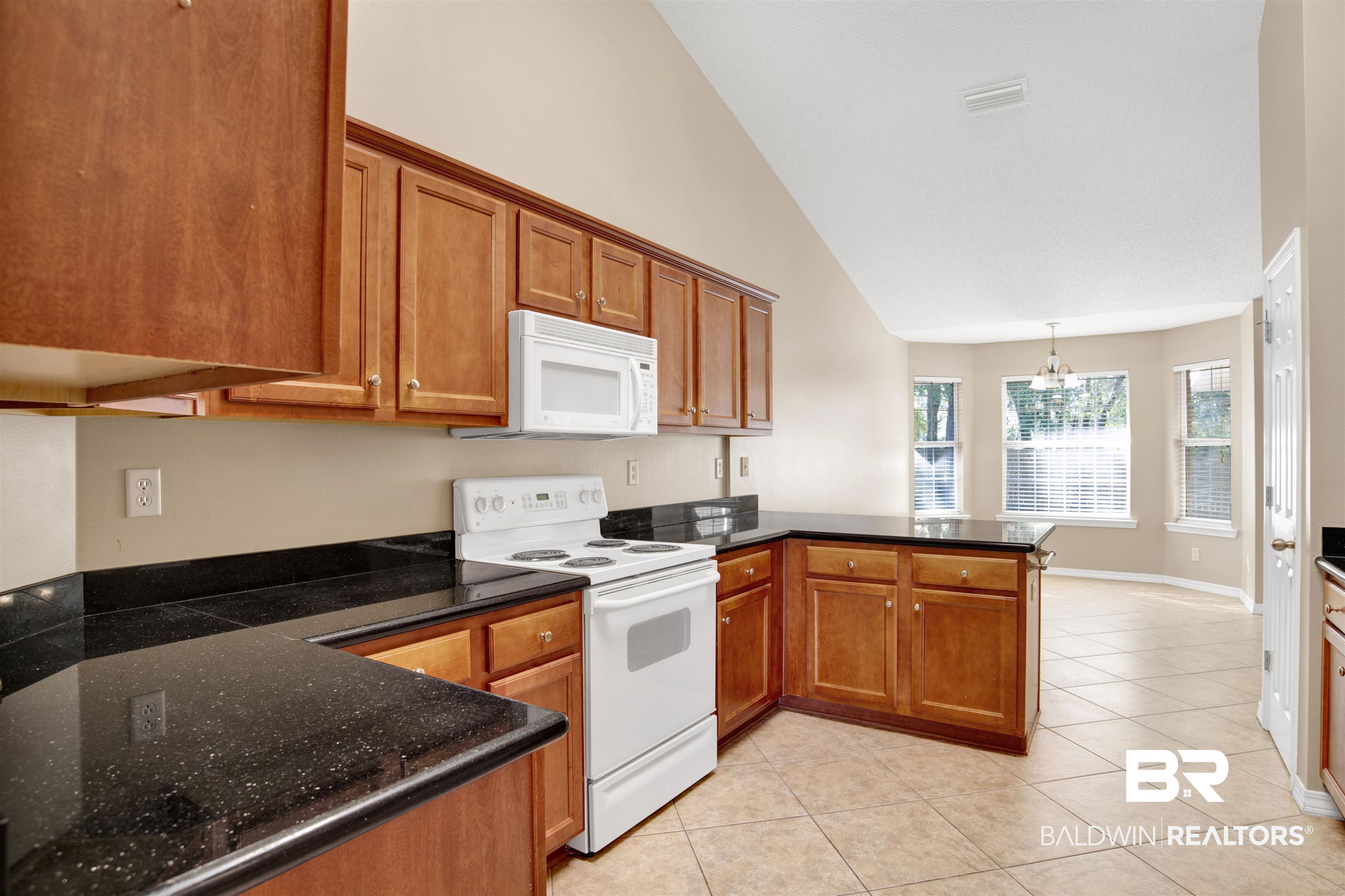 7297 Bridgemill Drive Mobile, AL 36619 - Photo 12 of 33 Kitchen with a peninsula, white appliances, brown cabinetry, high vaulted ceiling, and light tile patterned flooring