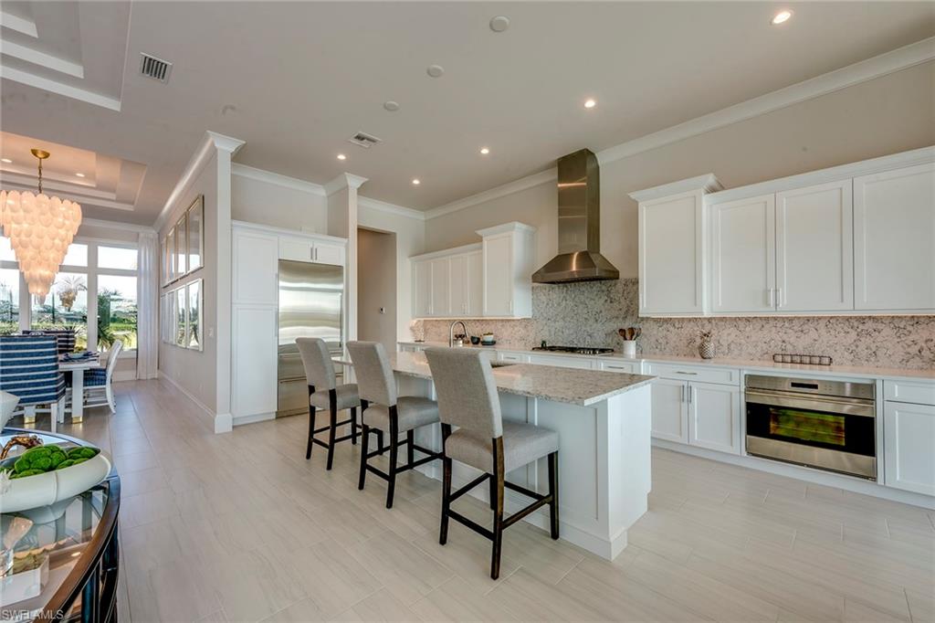 9828 Montiano Place Naples, FL 34113 - Photo 16 of 30 a kitchen with a table chairs stove and cabinets