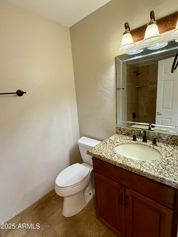 a bathroom with a granite countertop toilet a mirror and a sink