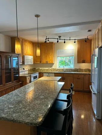 a kitchen with stainless steel appliances granite countertop a sink a stove and a wooden floors