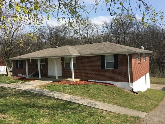 a front view of a house with a yard and trees