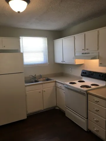 a kitchen with cabinets appliances a sink and a window