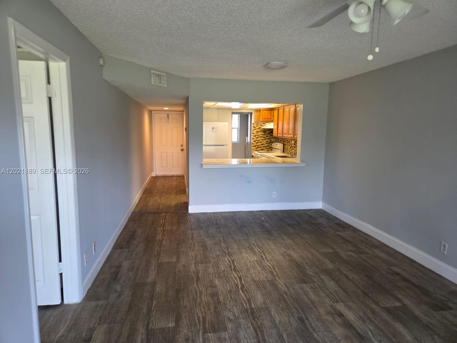 8060 North Colony Circle, Unit 103 Tamarac, FL 33321 - Photo 5 of 8 an empty room with wooden floor and windows