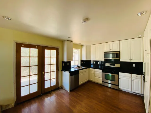 a kitchen with stainless steel appliances a stove top oven a sink a counter space and cabinets