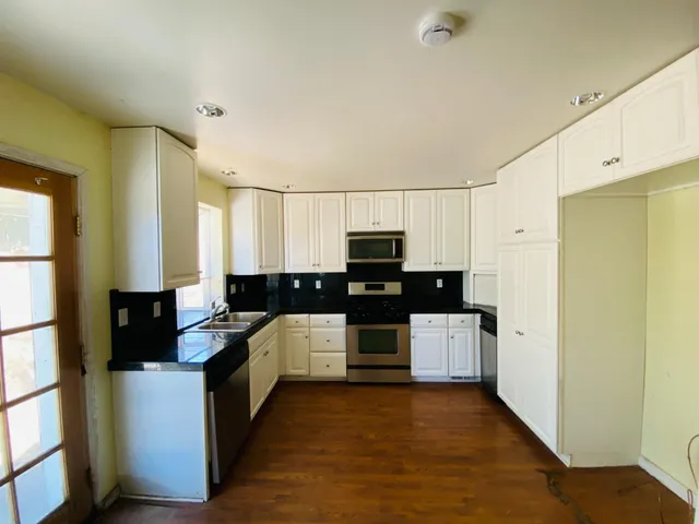 a large kitchen with a counter top space a sink a refrigerator and cabinets