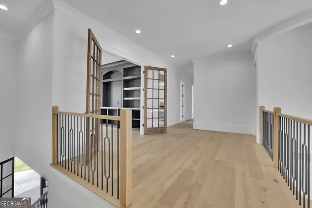 an empty room with large windows and ceiling fan