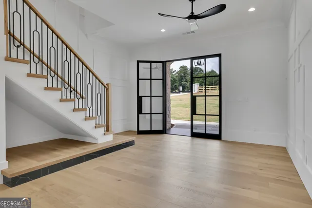 a view of an empty room with wooden floor and fan