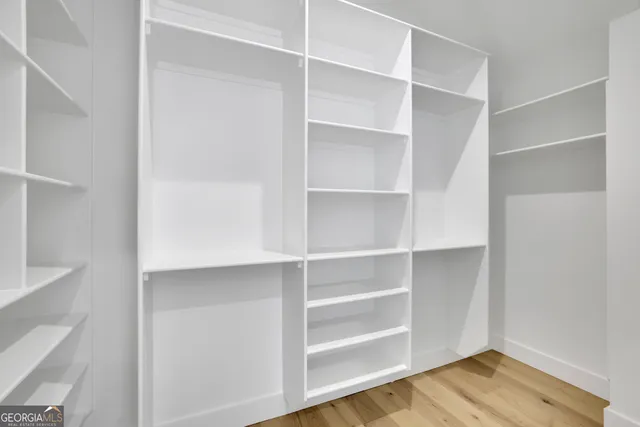 a view of an empty room with a window and a kitchen