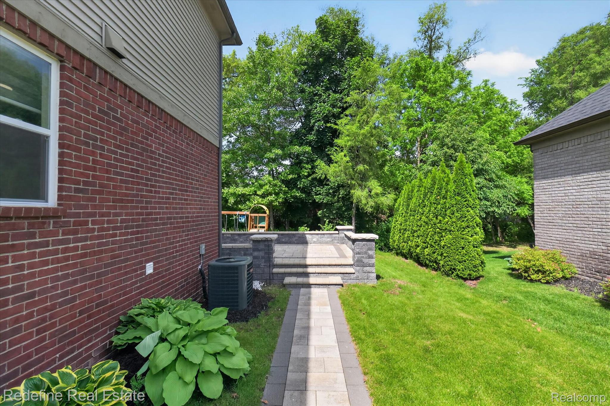 2976 Andlaur Drive Rochester, MI 48307 - Photo 44 of 60 Exterior brick and siding combination, featuring a paver walkway leading to a multi-tiered stone patio with integrated steps