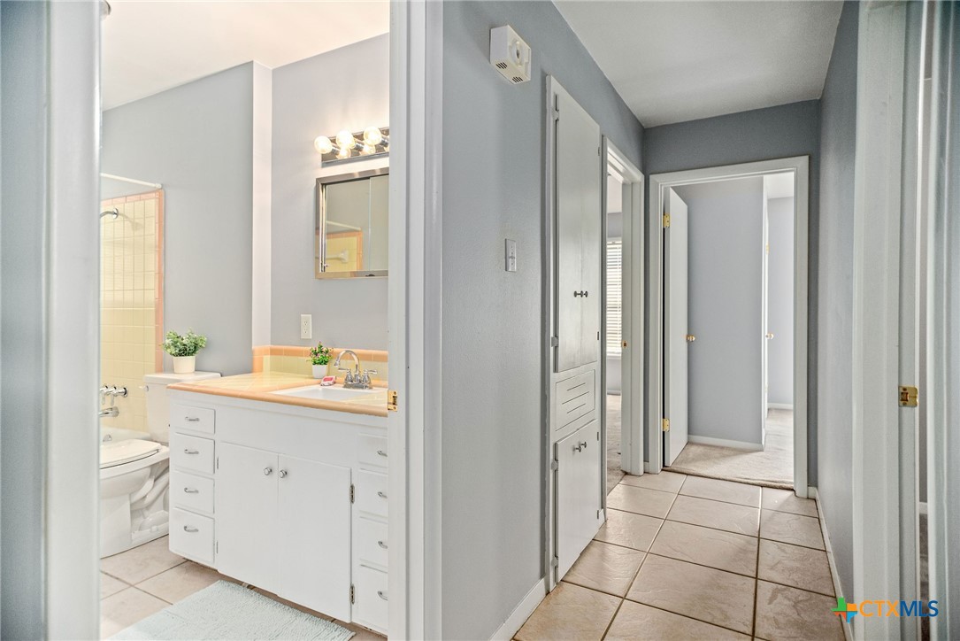 525 Travis Street Port Lavaca, TX 77979 - Photo 14 of 24 a bathroom with a granite countertop sink a toilet and a mirror