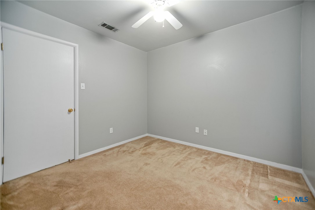 525 Travis Street Port Lavaca, TX 77979 - Photo 20 of 24 an empty room with a ceiling fan and carpet