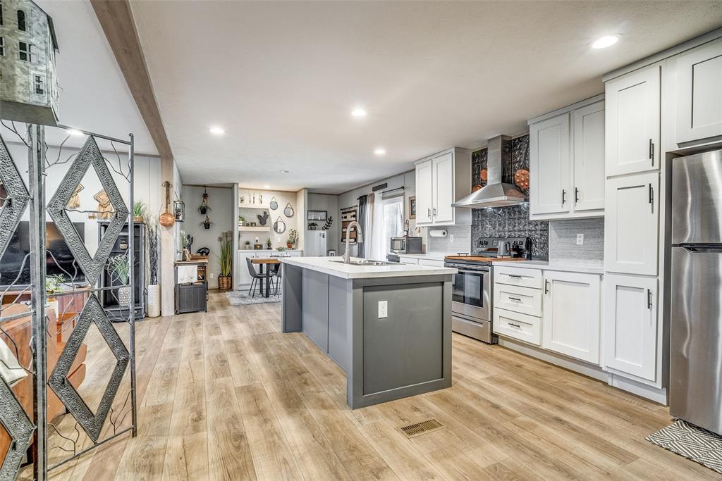 344 Hometown Way Springtown, TX 76082 - Photo 5 of 13 a kitchen with stainless steel appliances kitchen island granite countertop a refrigerator a sink dishwasher and white cabinets with wooden floor