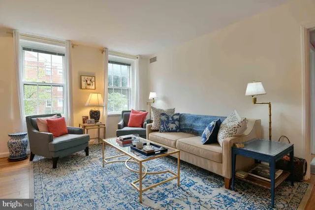 a living room with furniture a rug a lamp and a window