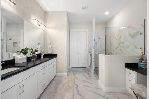 a spacious bathroom with a granite countertop sink a mirror and a shower