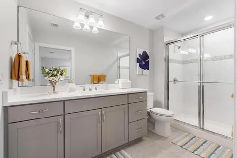 a bathroom with a toilet sink double vanity and mirror