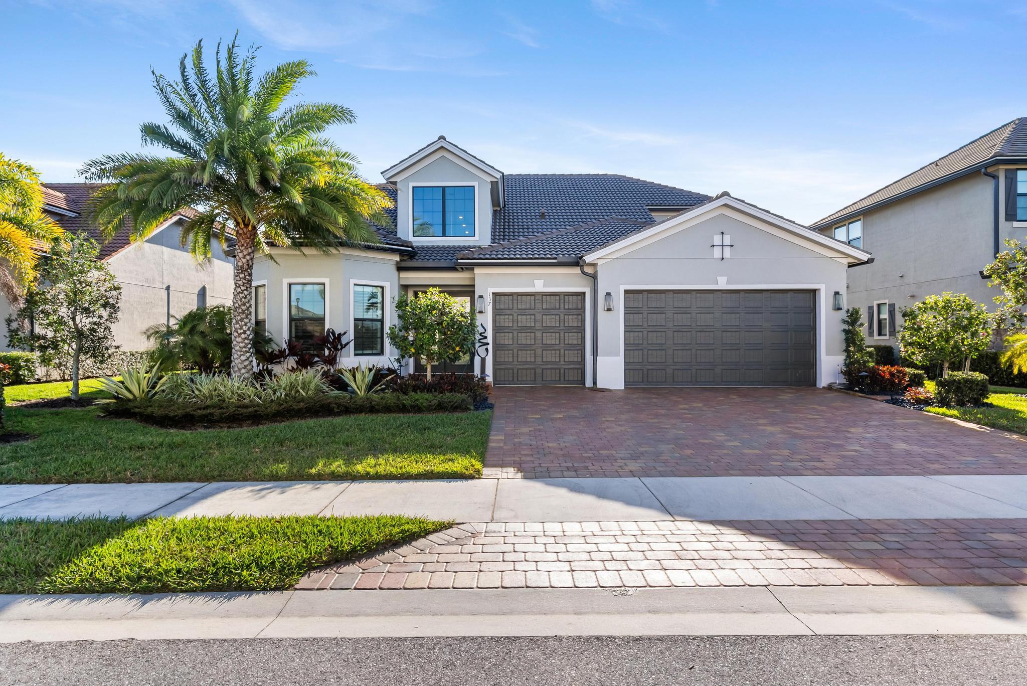137 Cinder Dunes Point Jupiter, FL 33478 - Photo 41 of 45 a front view of a house with a garden and yard