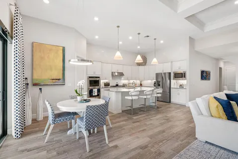 a kitchen with a dining table chairs wooden floor appliances and cabinets