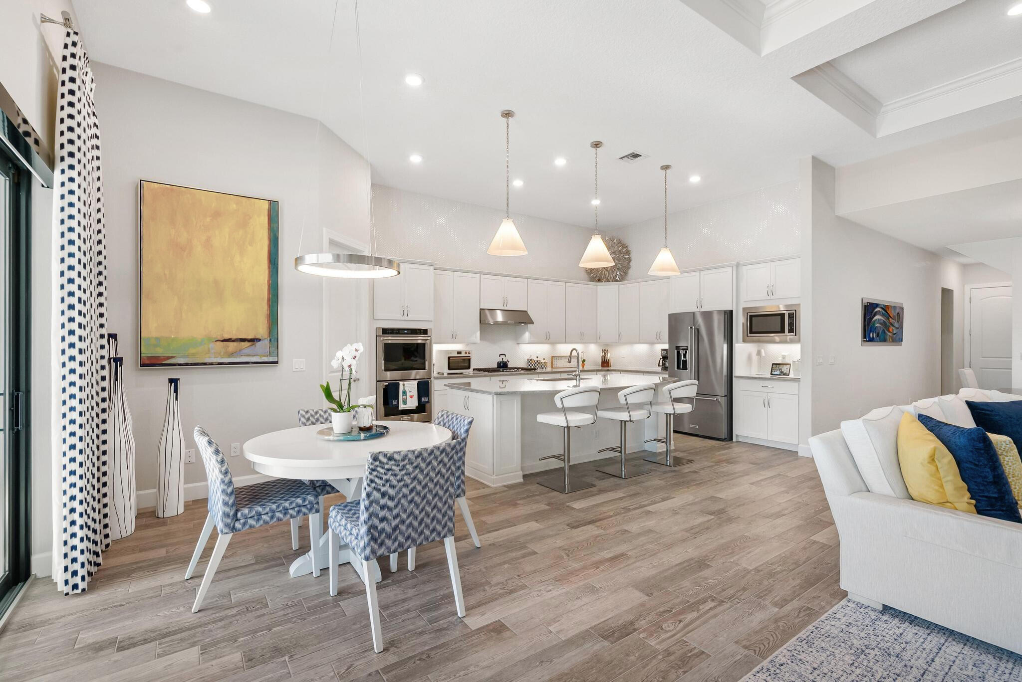 137 Cinder Dunes Point Jupiter, FL 33478 - Photo 6 of 45 a kitchen with a dining table chairs wooden floor appliances and cabinets