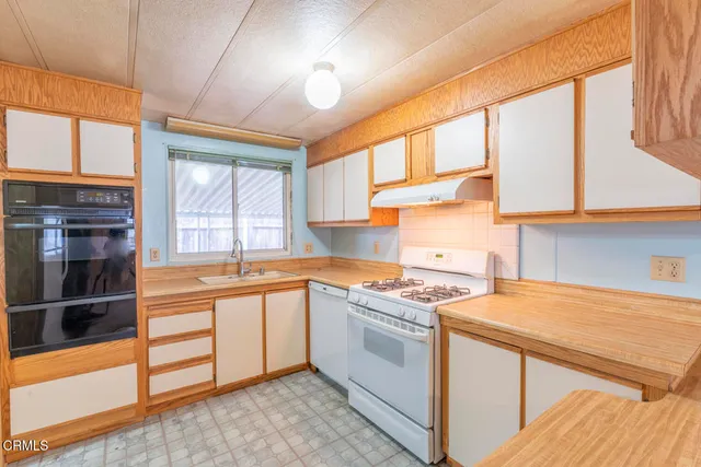 a kitchen that has a lot of cabinets in it and wooden floors