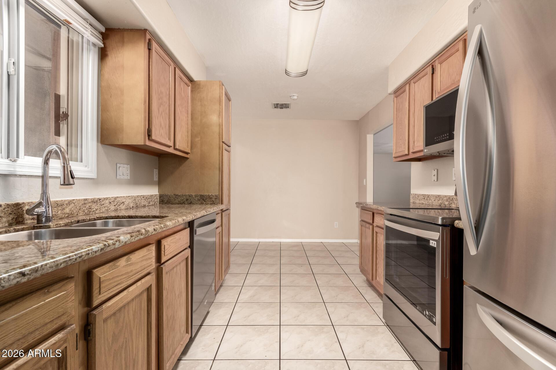 3613 South Kenneth Place Tempe, AZ 85282 - Photo 9 of 17 a kitchen with stainless steel appliances granite countertop a stove a sink and a refrigerator
