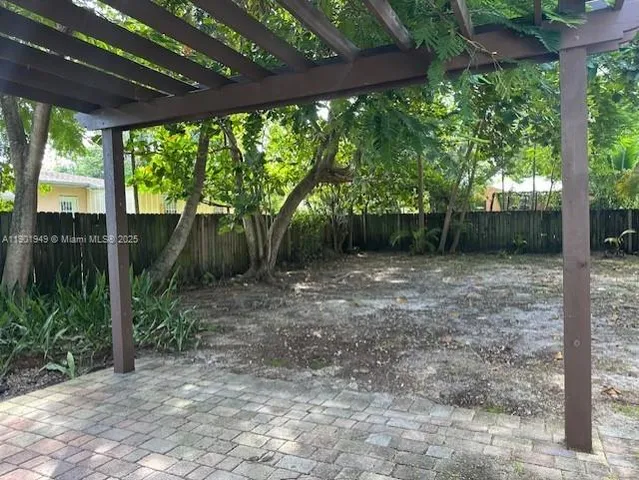a backyard of a house with large trees and outdoor seating